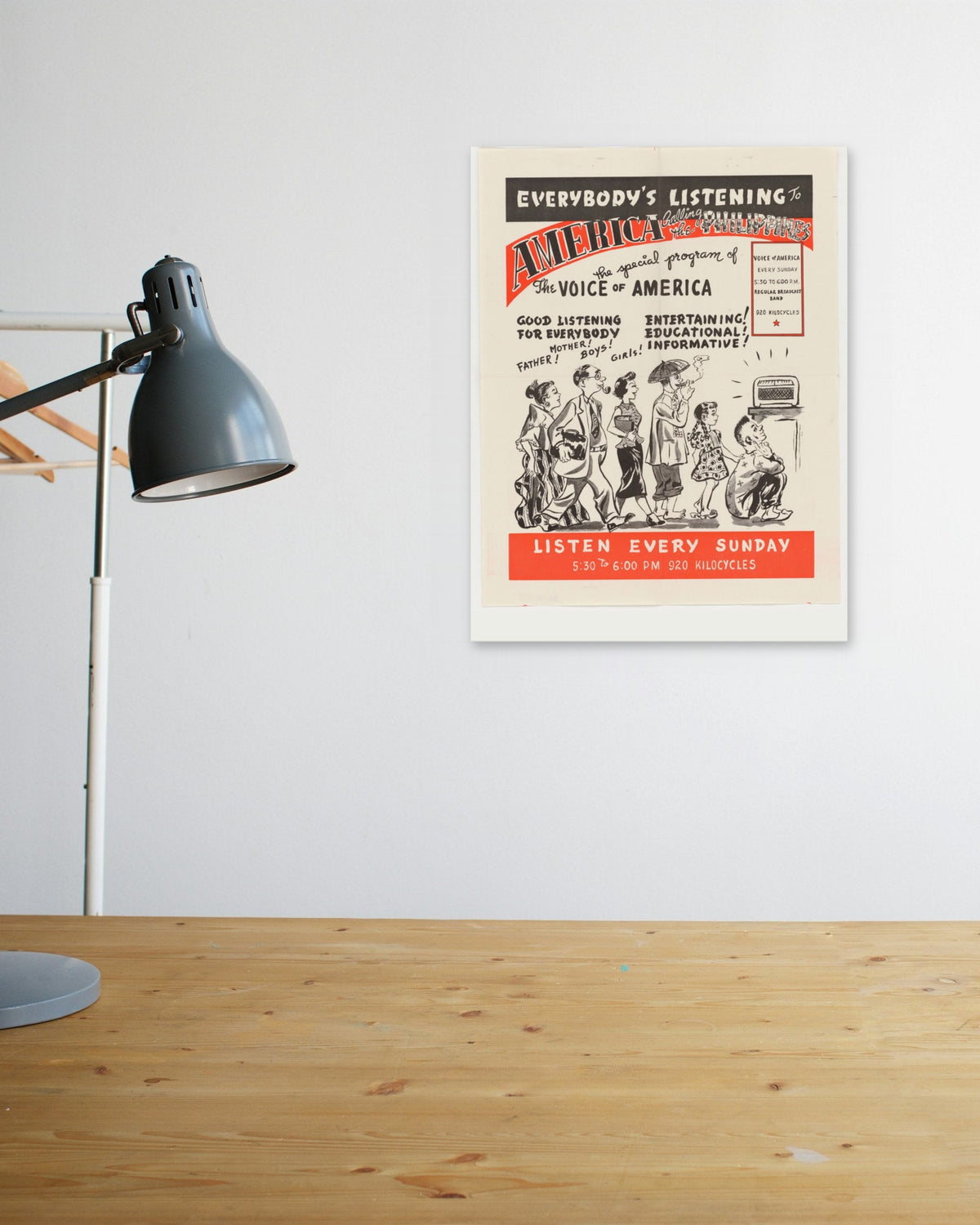 "Everybody's Listening to America!" poster above a wooden desk