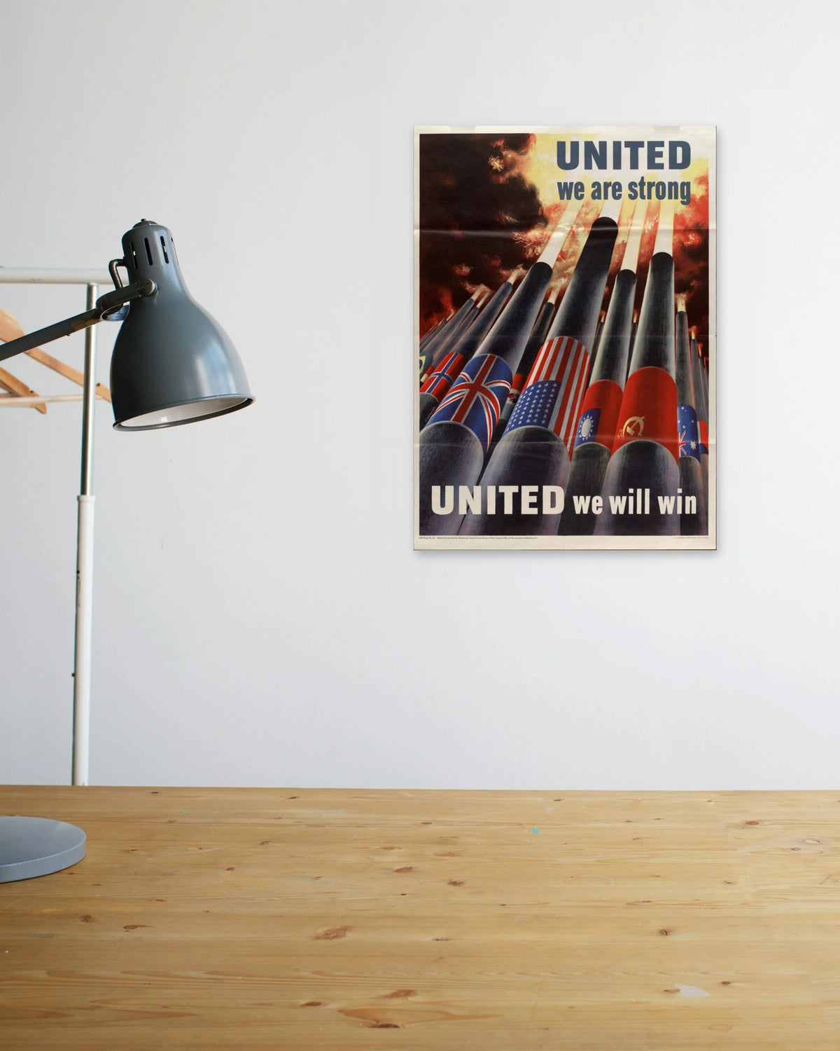 "United We Are Strong – United We Will Win" poster above a wooden desk