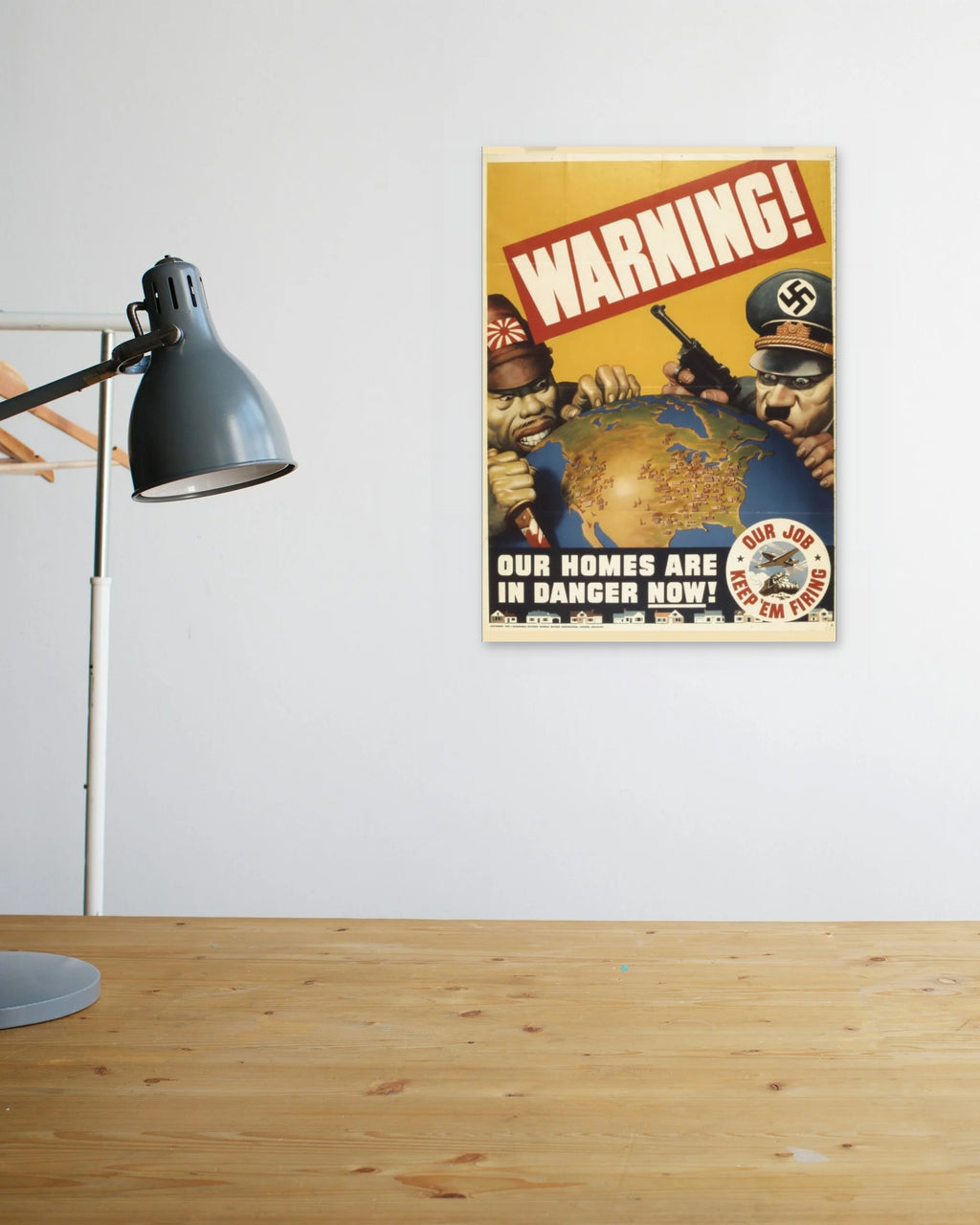 "Warning! Our Homes Are in Danger Now" poster above a wooden desk