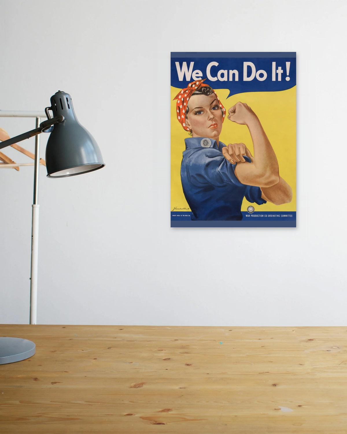"We Can Do It!" poster above a wooden desk