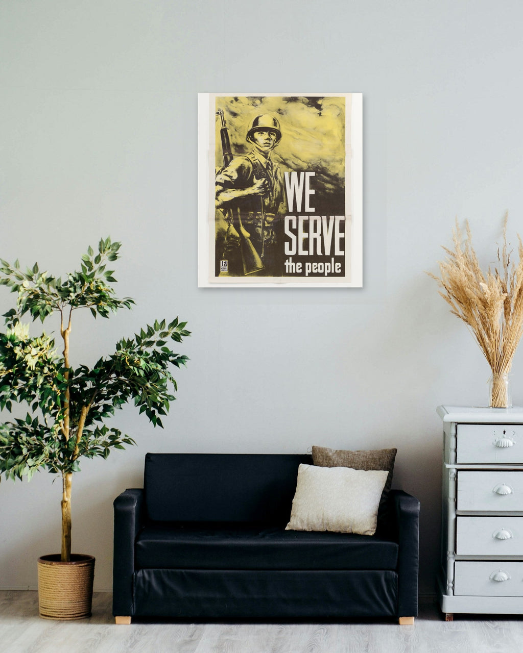 "We Serve the People" poster on a living room wall