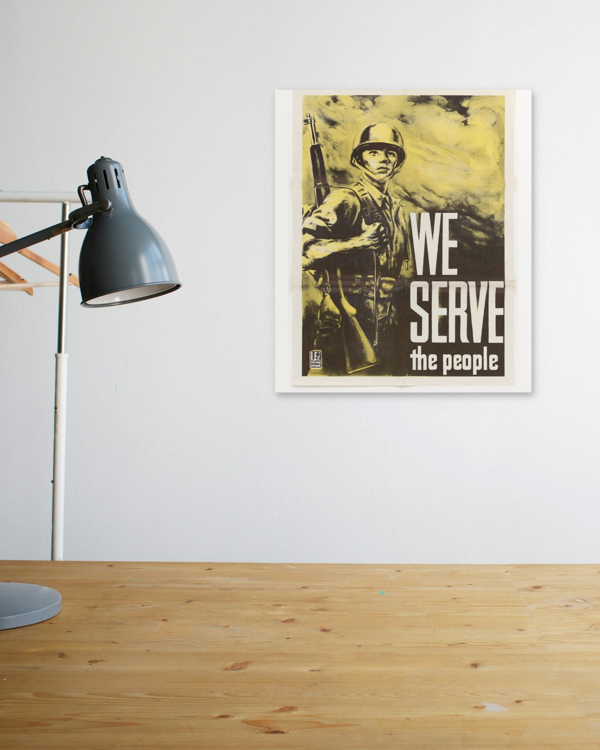 "We Serve the People" poster above a wooden desk