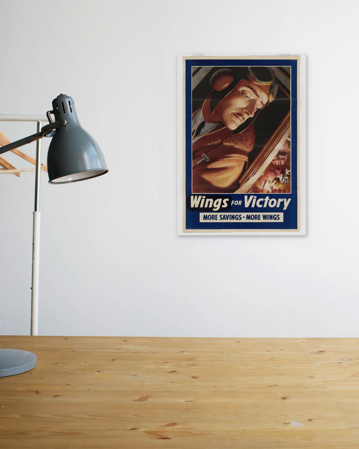 "Wings for Victory" poster above a wooden desk
