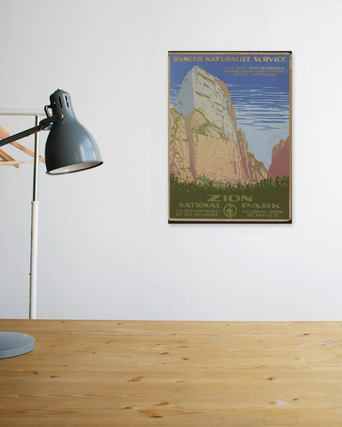 "Zion National Park" poster above a wooden desk
